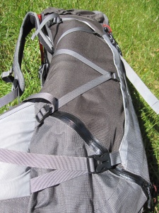 Vue latérale : zip étanche en bas du sac, et 2 sangles de compression latérales : une en bas et une qui serpente sur la hauteur