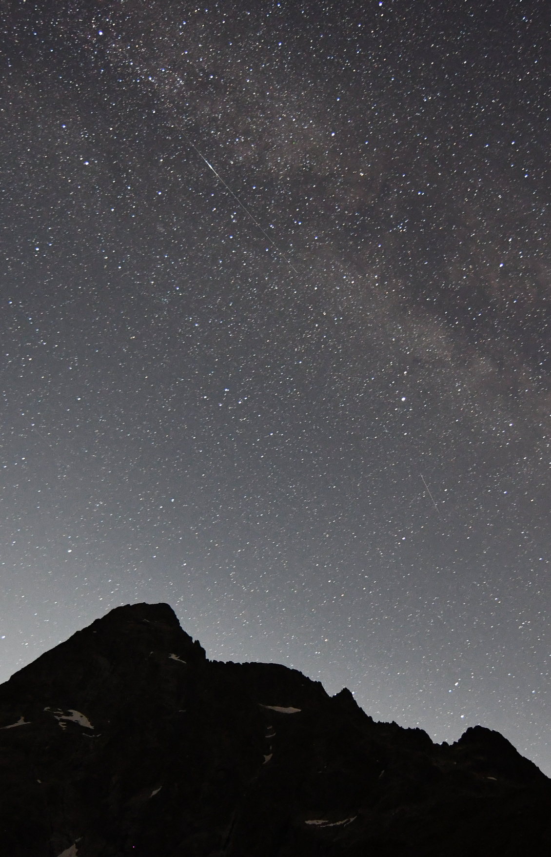 Étoile filante ténue parallèle à la Voie lactée juste au-dessus du sommet du Sirac dans les Écrins.
