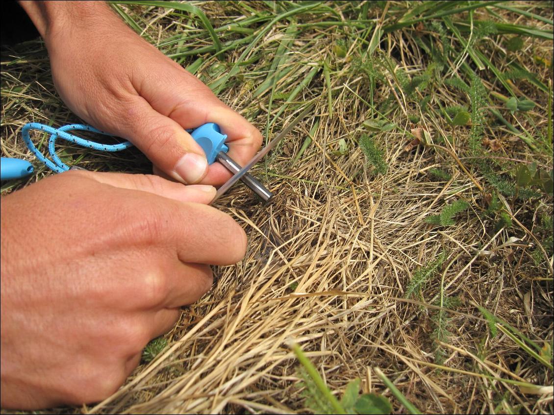 Comment allumer un feu avec un FireSteel : faire courir le couteau en appui assez fort (privilégier la force plus que la rapidité pour faire de grosses étincelles efficaces)